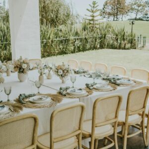 Chic outdoor table setting for a celebration with white decor and natural elements.
